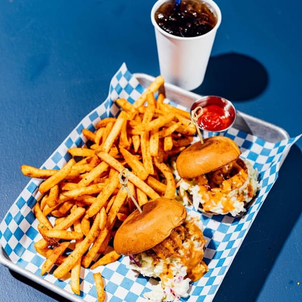 Two Shark Boy Fish and Chips sliders with fries, ketchup, and a soda on a blue table.