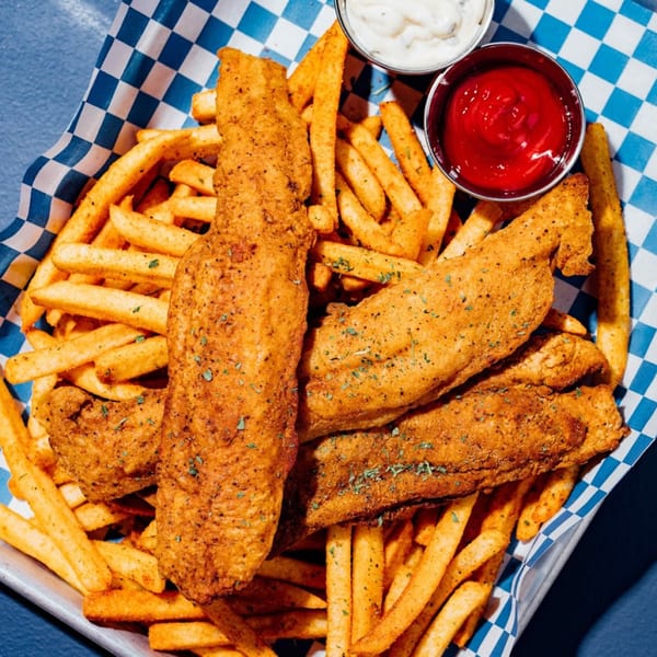 Crispy Shark Boy fish and chips with tartar sauce and ketchup in a metal basket.