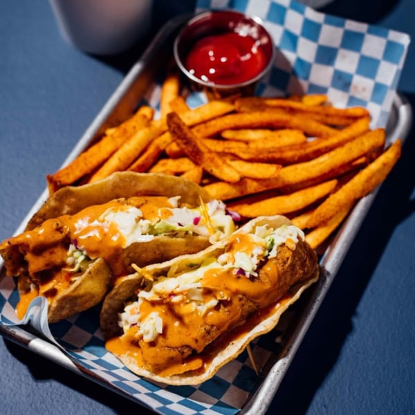 Two Shark Boy fish tacos with slaw and orange sauce, served with fries and ketchup on a tray.